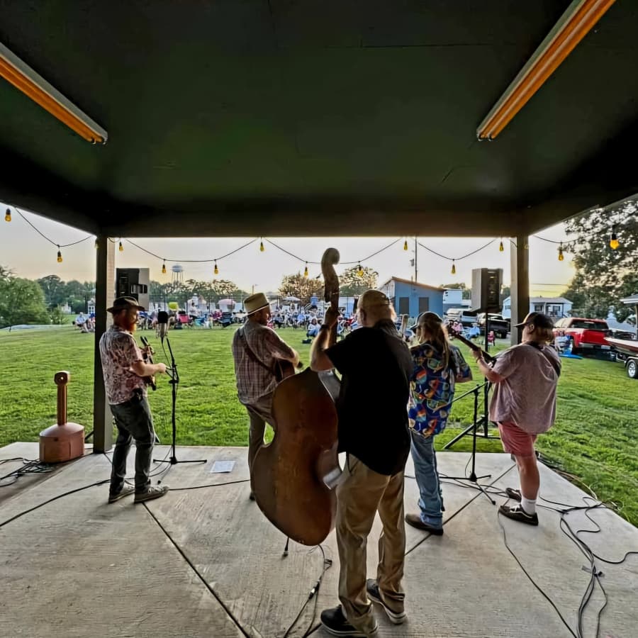 A group of musicians performs on stage while an audience enjoys the show in the background.