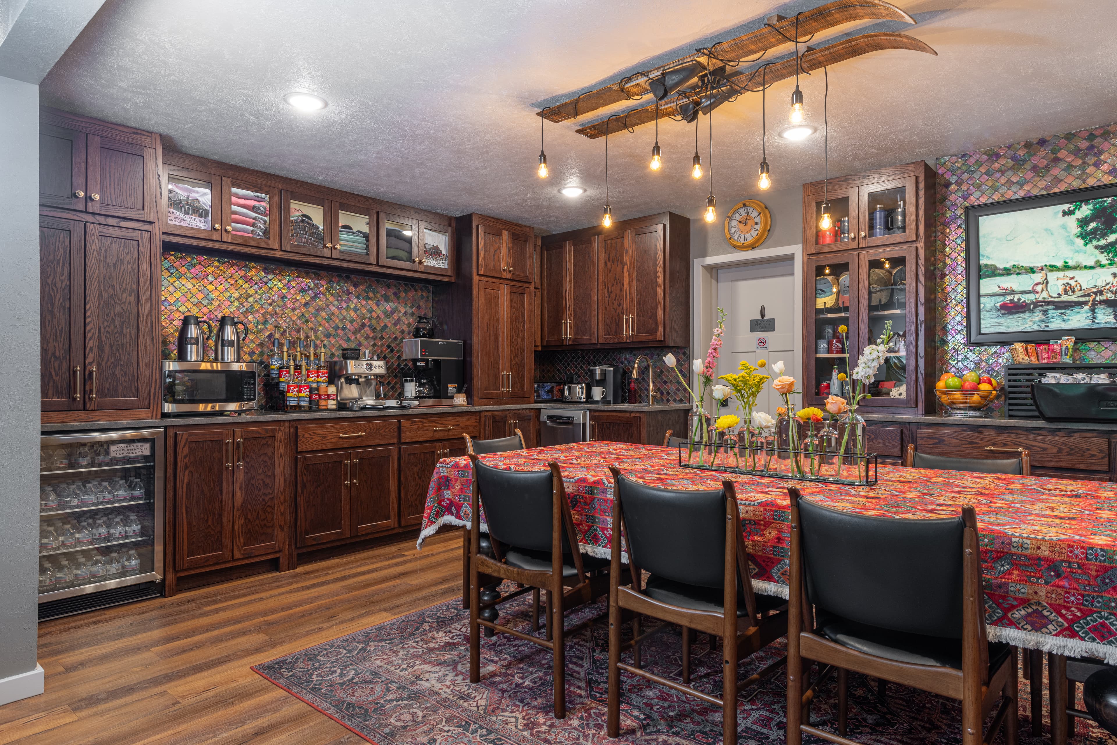 A warm and inviting kitchen featuring wooden cabinetry, colorful tiles, and a dining table set with flowers.