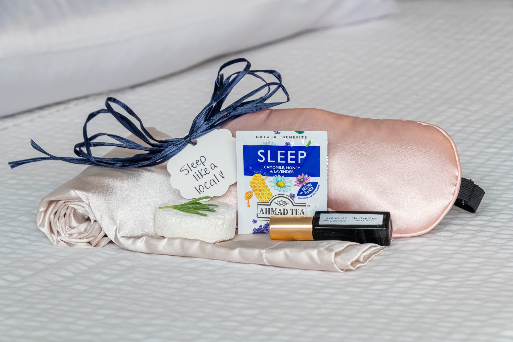 A sleep kit featuring a silk eye mask, herbal tea, a calming essential oil, and a note saying "Sleep like a local."