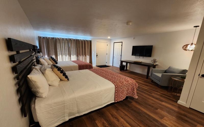 two queen beds with table desk, television and hanging lamp