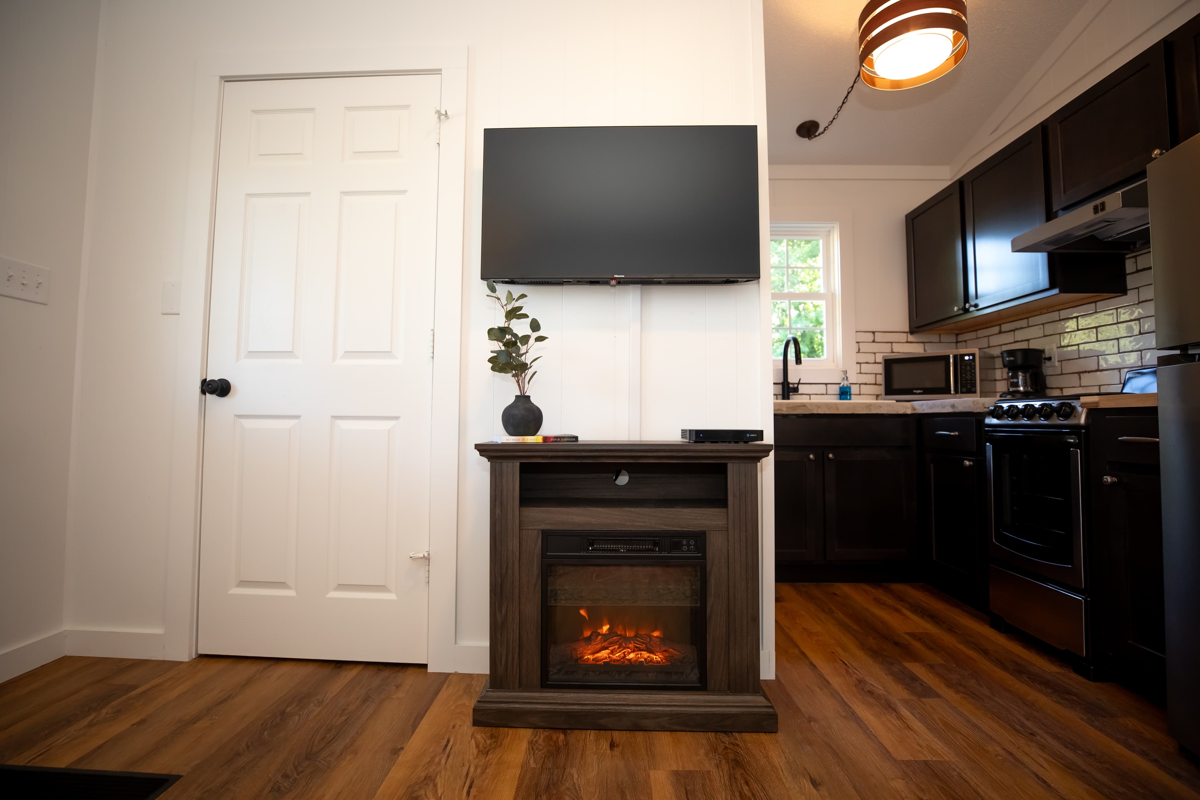 full kitchen with sink, microwave, toaster, coffeemaker, refrigerator, plus an electric fireplace and television