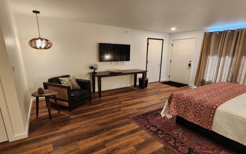 table with television mounted on wall above it with chair and hanging lamp