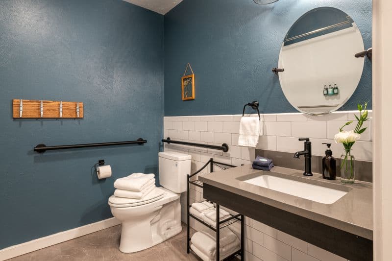 large private bath with toilet with grab bars, accessible sink vanity