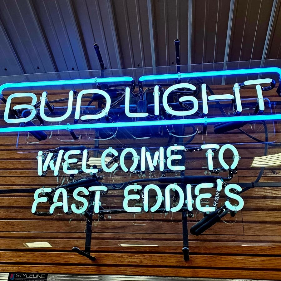 Neon sign displaying "Bud Light" and "Welcome to Fast Eddie's."