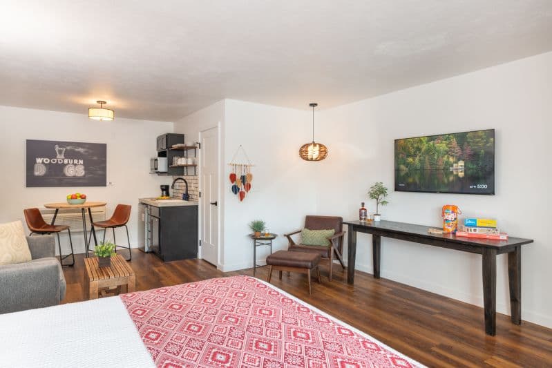 table with television mounted on wall above it with chair and hanging lamp