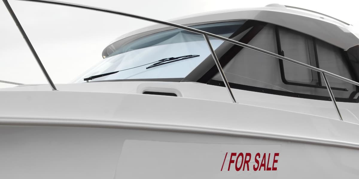 Close-up of a boat with a "For Sale" sign on its side.