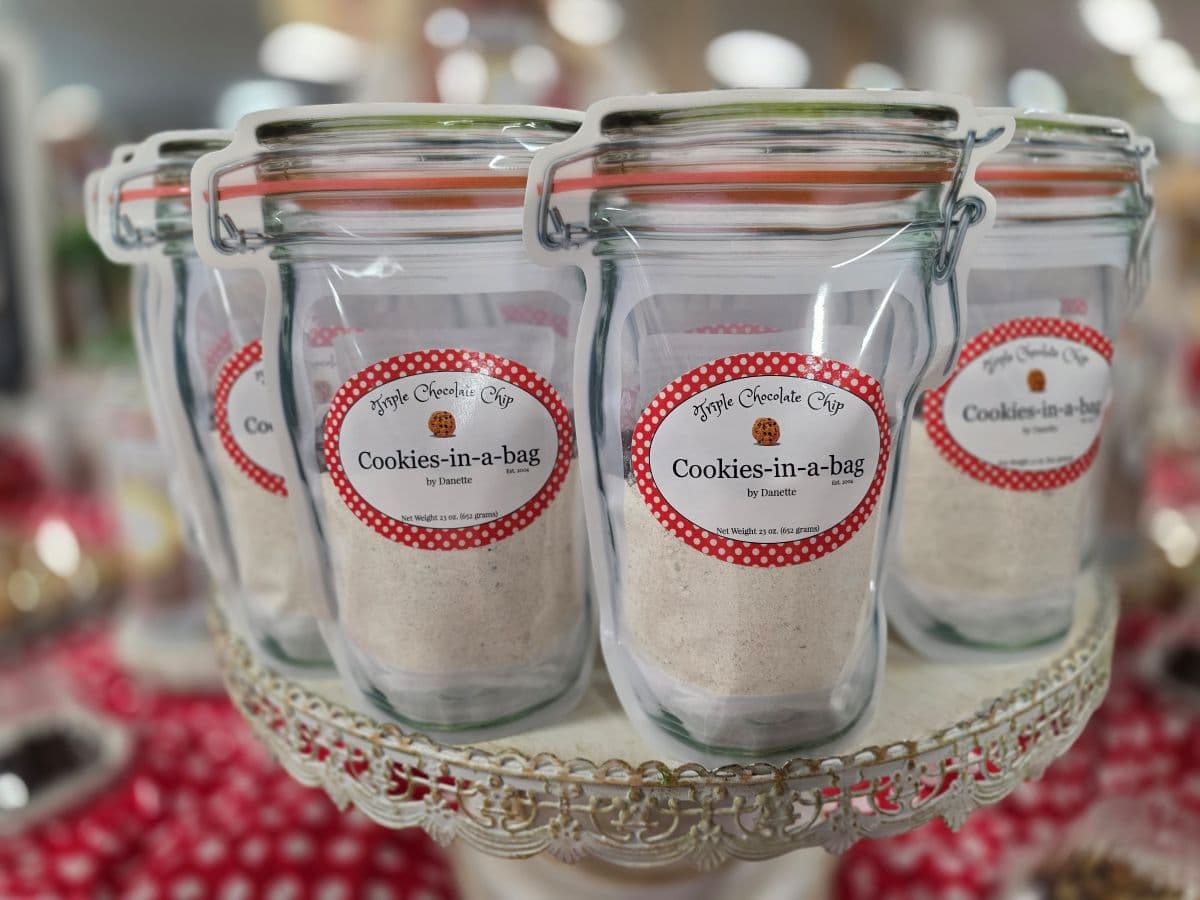 A display of glass jars filled with cookie mix labeled "Cookies-in-a-bag." A display of glass jars filled with cookie mix labeled "Cookies-in-a-bag."
