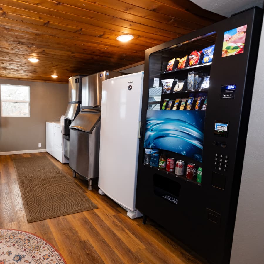 A kitchen featuring stainless steel appliances and a black vending machine stocked with snacks and beverages.