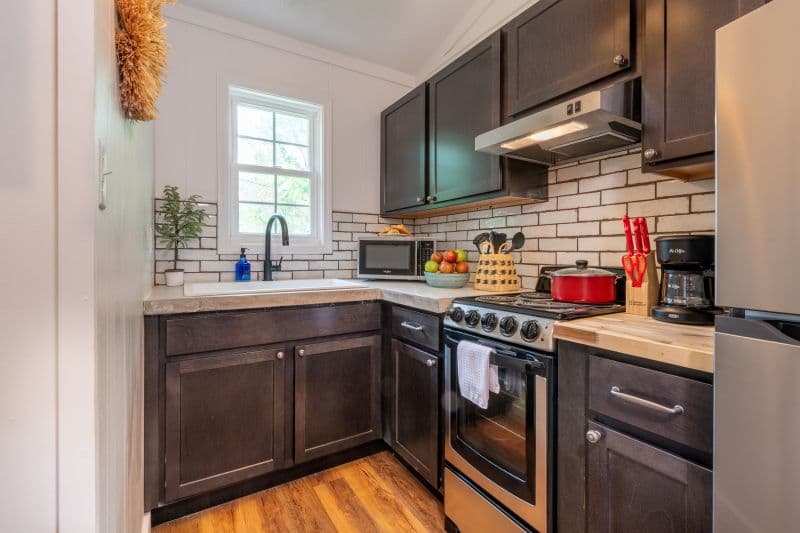 full kitchen with sink, microwave, toaster, coffeemaker, refrigerator, plus an electric fireplace and television