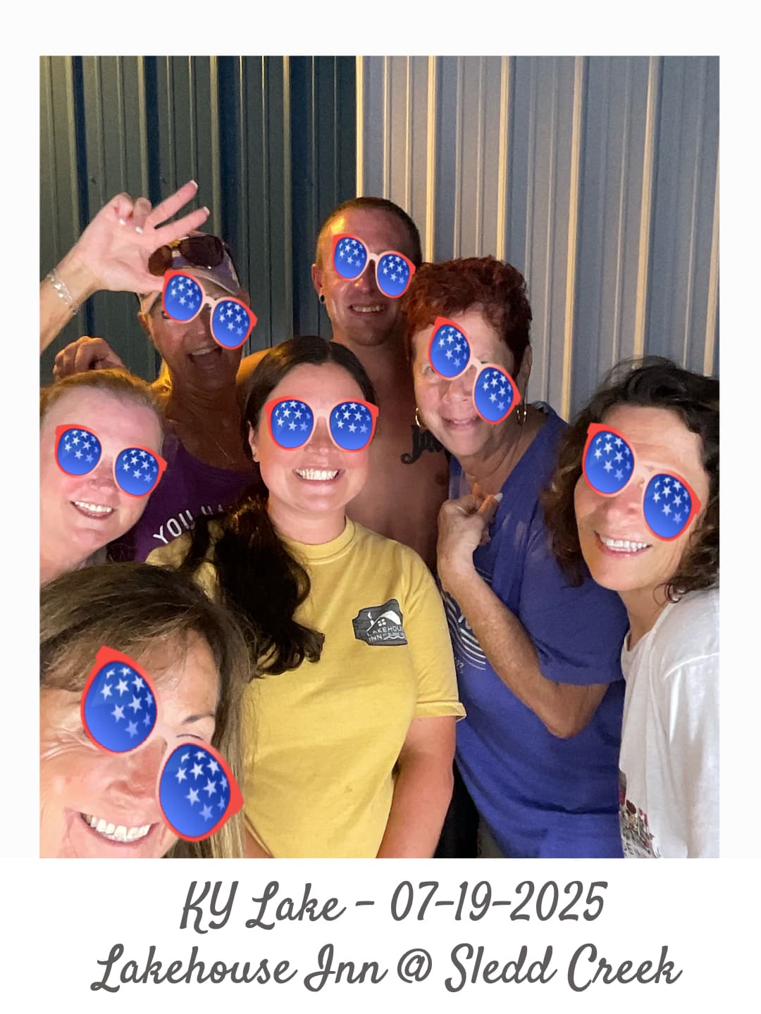 A group of seven friends poses playfully at a lakehouse, wearing sunglasses decorated with star motifs.
