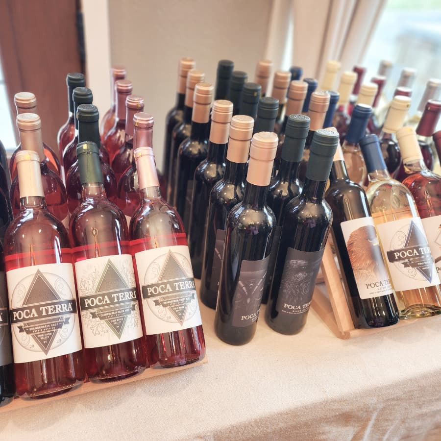 A display of various wine bottles labeled "Poca Terra" on a table.