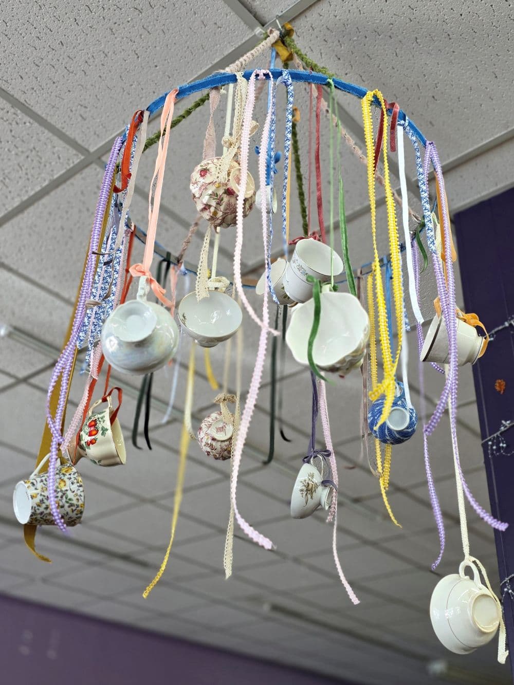 A hanging mobile adorned with various teacups and colorful ribbons.