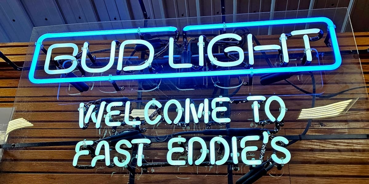 Neon sign reading "Bud Light" and "Welcome to Fast Eddie's."