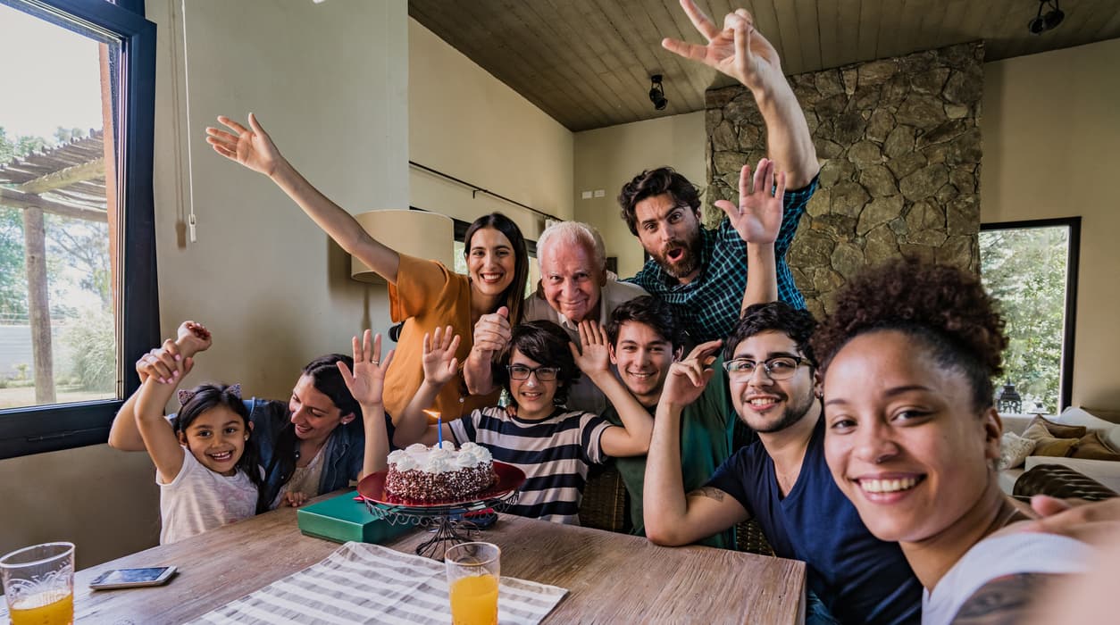 A joyful group of people celebrating with a cake at a gathering.