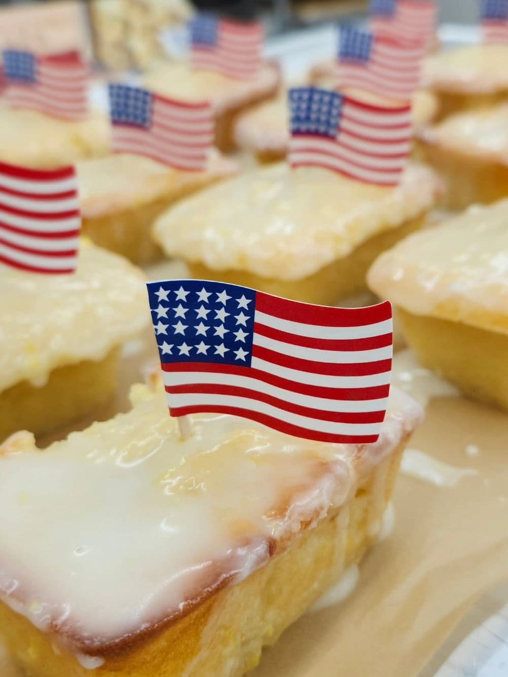 Mini cakes topped with icing and small American flags.