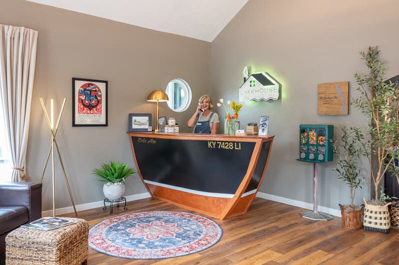 A smiling woman at a stylish reception desk in a modern, inviting lobby. A smiling woman at a stylish reception desk in a modern, inviting lobby.