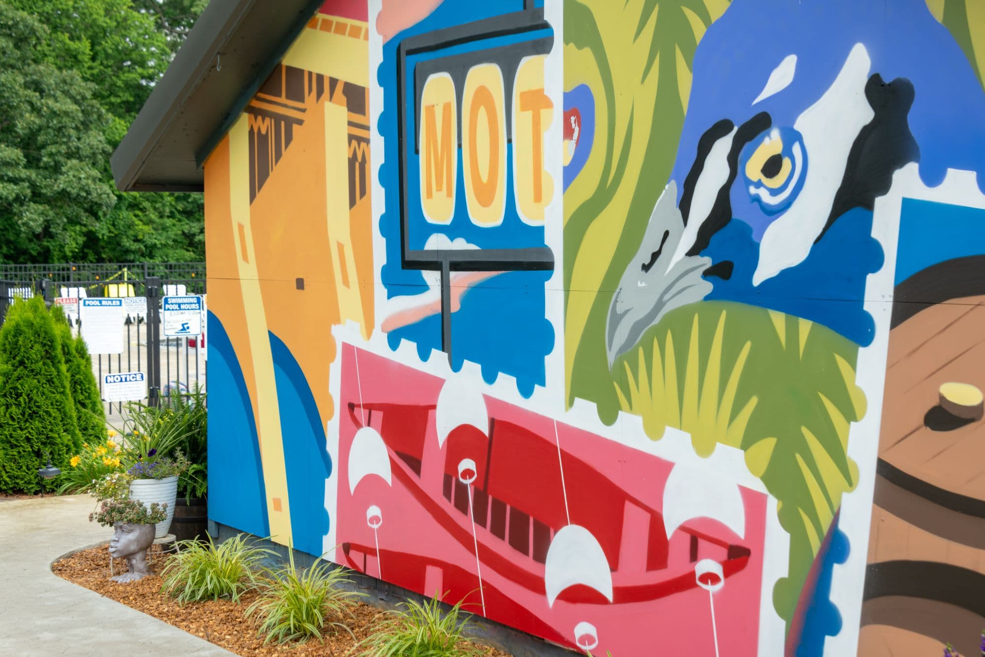 A vibrant mural featuring colorful designs, including a bird and boats, adorns a building exterior. A vibrant mural featuring colorful designs, including a bird and boats, adorns a building exterior.