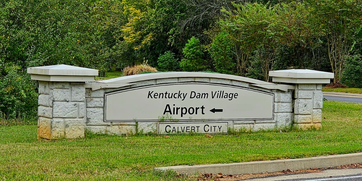 A directional sign for Kentucky Dam Village indicating the way to the airport and Calvert City.