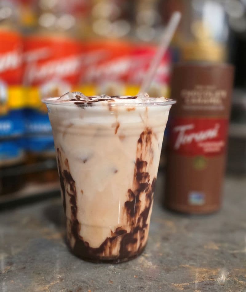 Iced chocolate and cream beverage in a clear cup with a straw.
