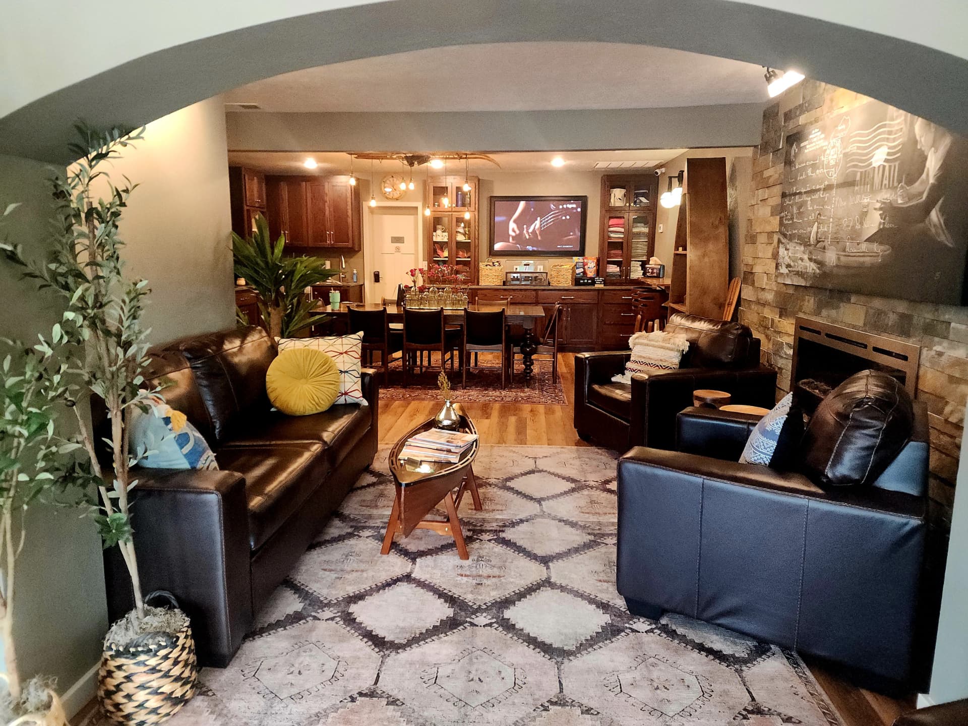A cozy living room featuring two leather sofas, a coffee table, and a view of a dining area and kitchen.