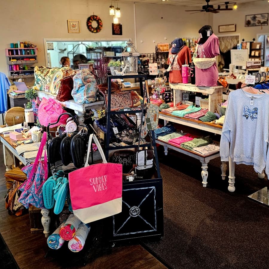 A vibrant boutique interior filled with colorful clothing and accessories displayed on tables and racks.