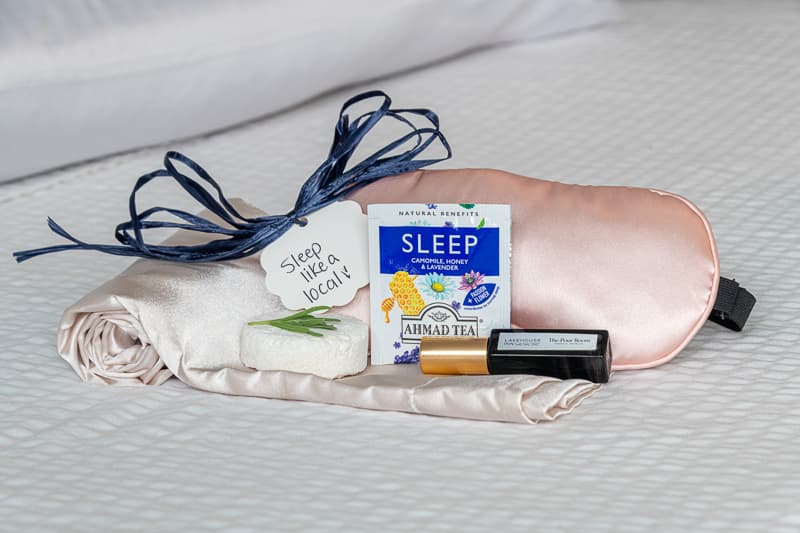 A sleep-themed relaxation kit featuring a sleep mask, herbal tea, and a note reading "Sleep like a local."