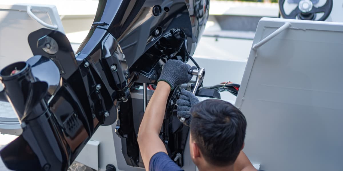 A person is repairing the engine of a boat.
