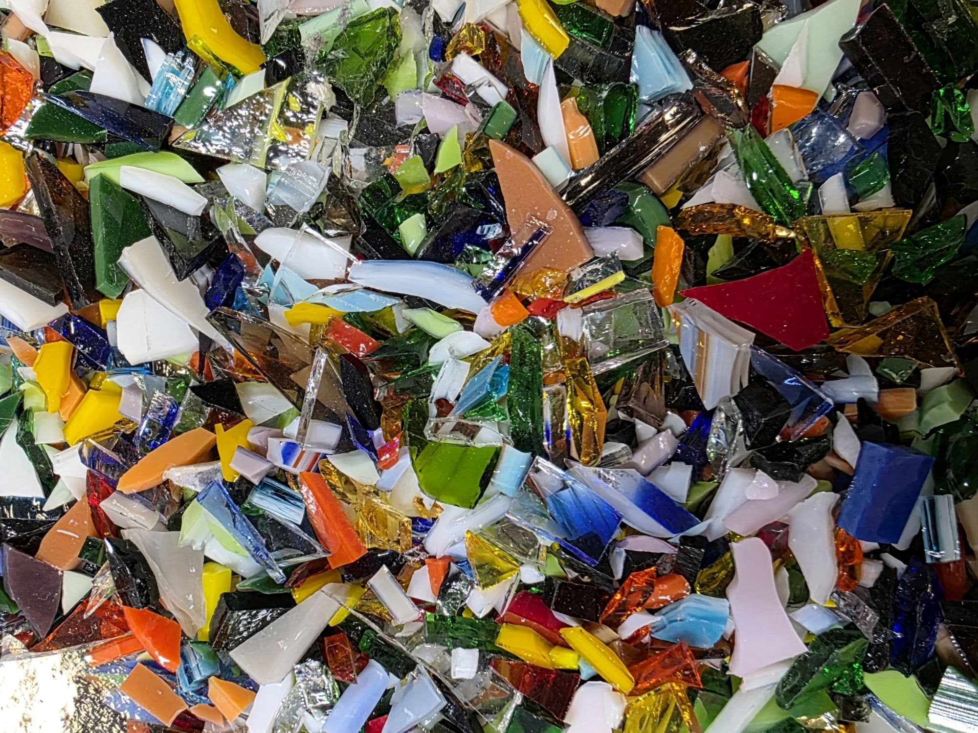 A colorful assortment of shattered glass pieces scattered on a surface. A colorful assortment of shattered glass pieces scattered on a surface.