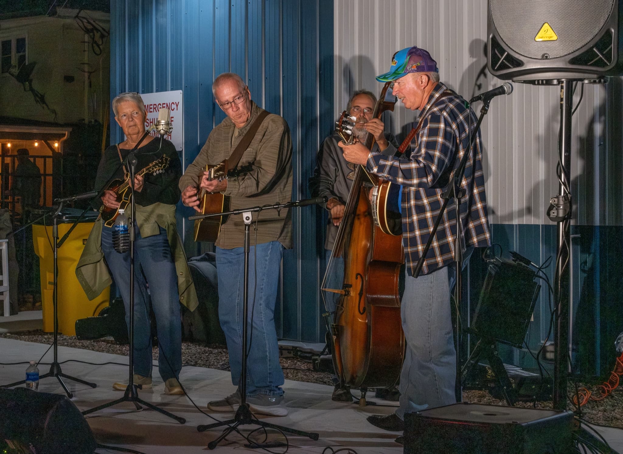 Four musicians play instruments on stage at a night event.