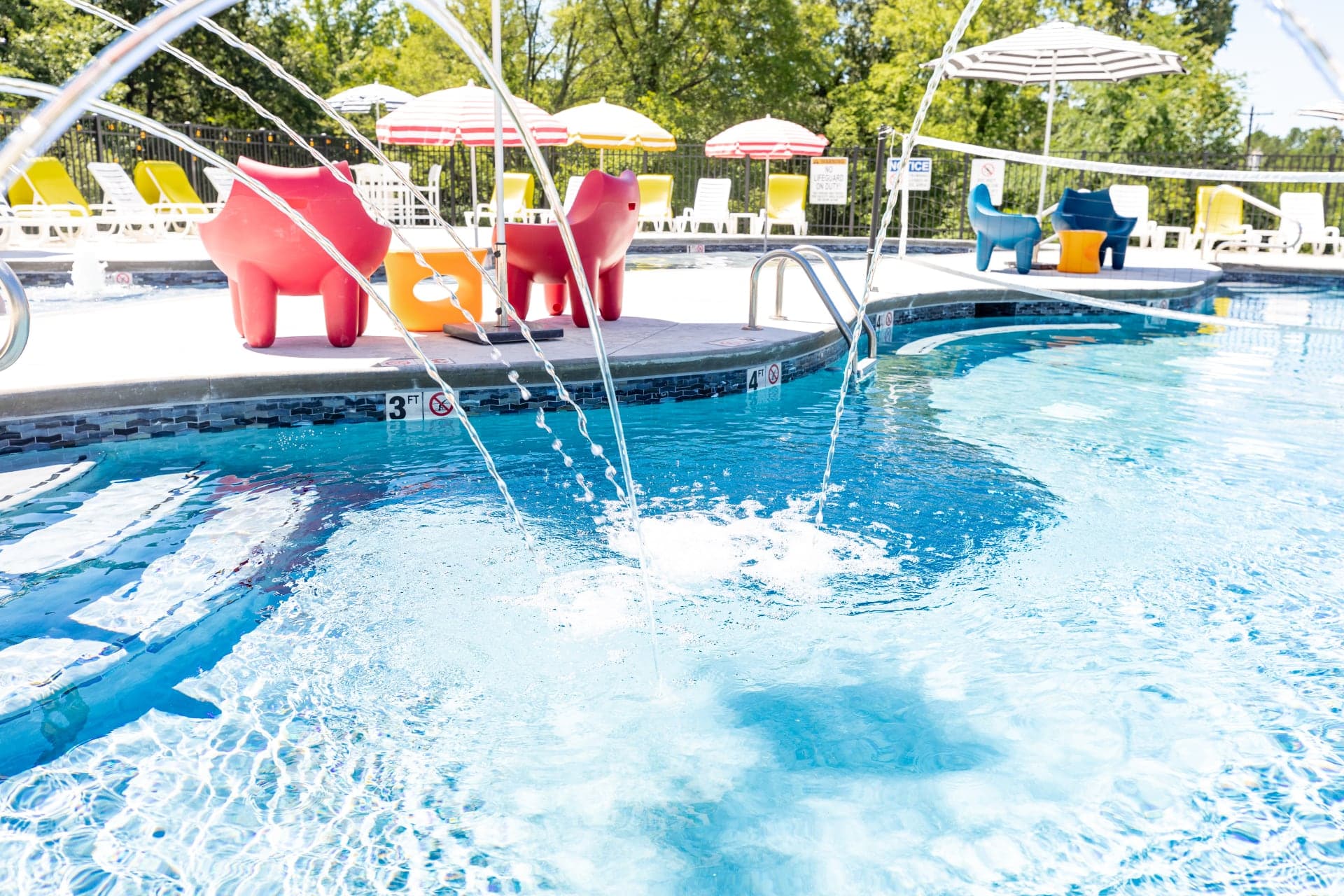 A vibrant swimming pool area featuring colorful seating and playful water fountains.