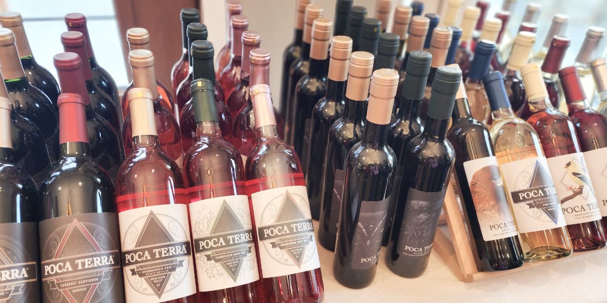 An assortment of wine bottles with various labels, predominantly featuring the name "Poca Terra."
