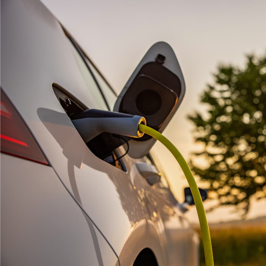 An electric vehicle is connected to a charging station with a yellow charging cable.