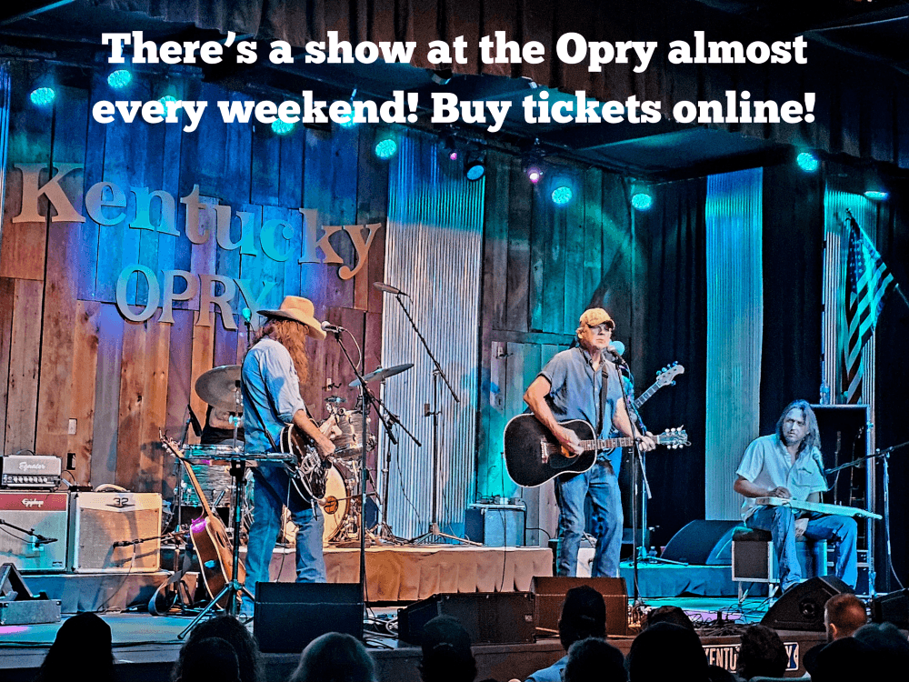 A live band performs on stage at the Kentucky Opry with colorful lighting and a lively audience.