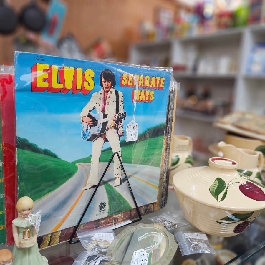 A vintage Elvis Presley album titled "Separate Ways" displayed in a thrift store with decorative items in the background.