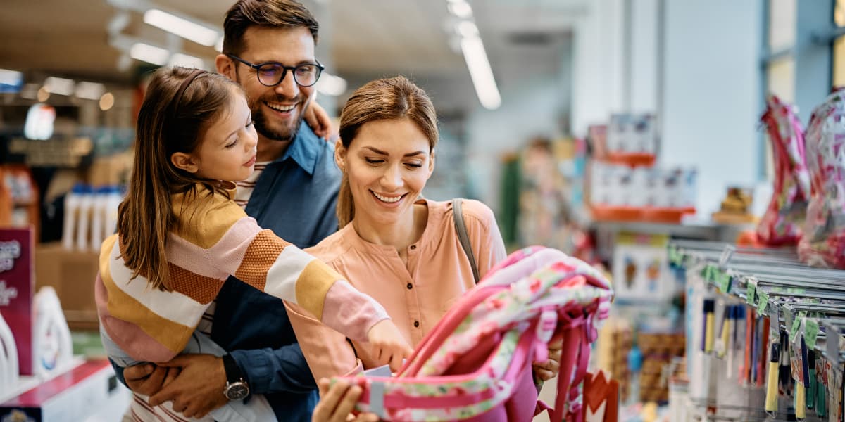 A family enjoys shopping together, examining a colorful backpack in a store.