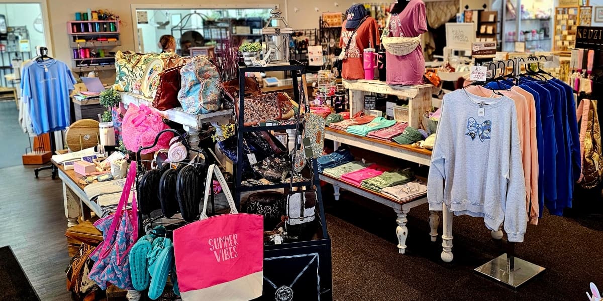 A colorful retail store display featuring clothing and accessories on racks and tables.