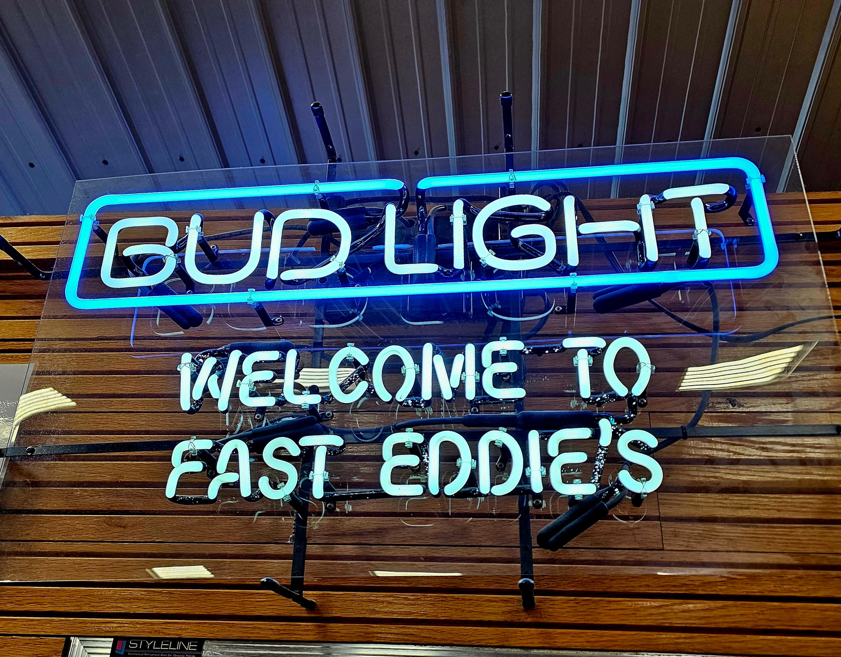 Neon sign for Bud Light welcoming guests to Fast Eddie's.