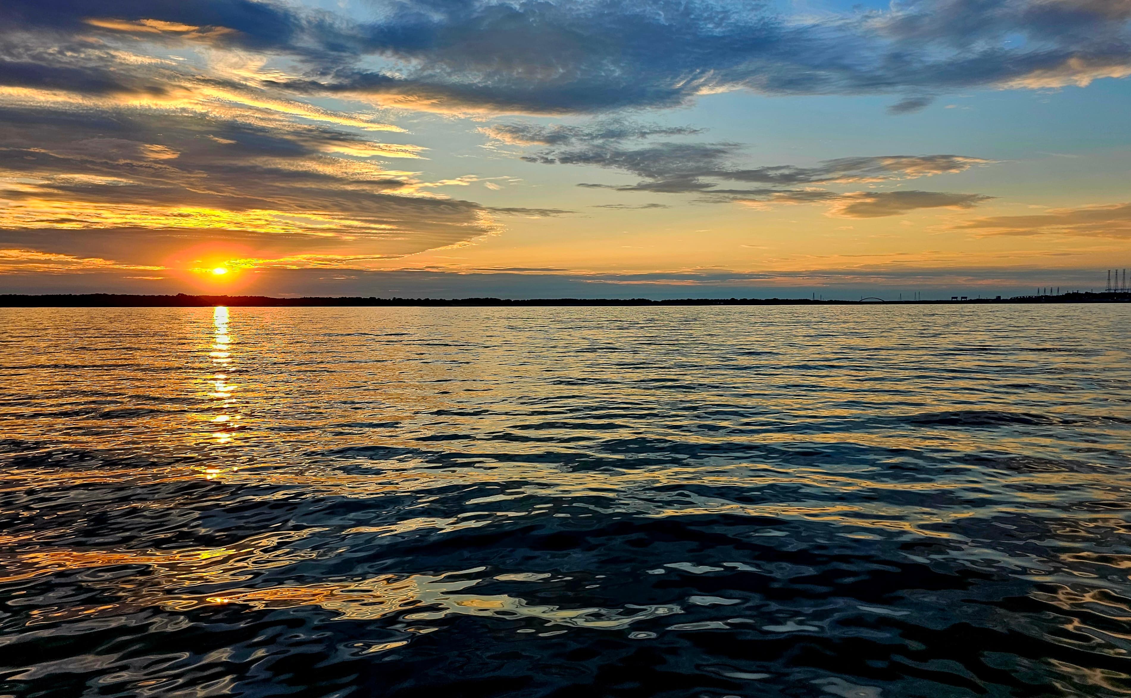 Sunset over calm waters, reflecting vibrant colors in the sky.
