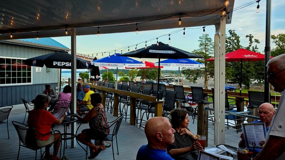 people sitting on a patio having dinner and drinks under red and blue umbrellas