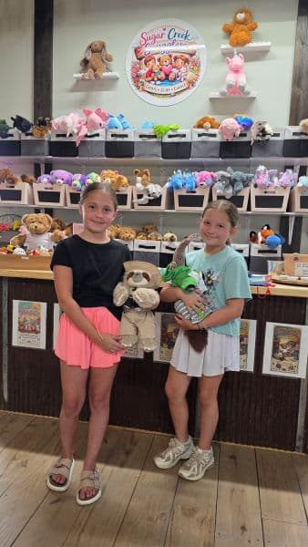 two girls holding stuffed animals dressed in fun outfits